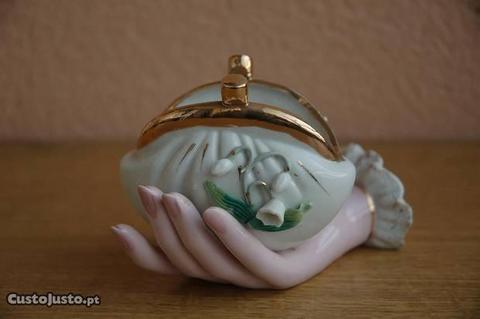 Mão segurando um porta moedas em porcelana antiga